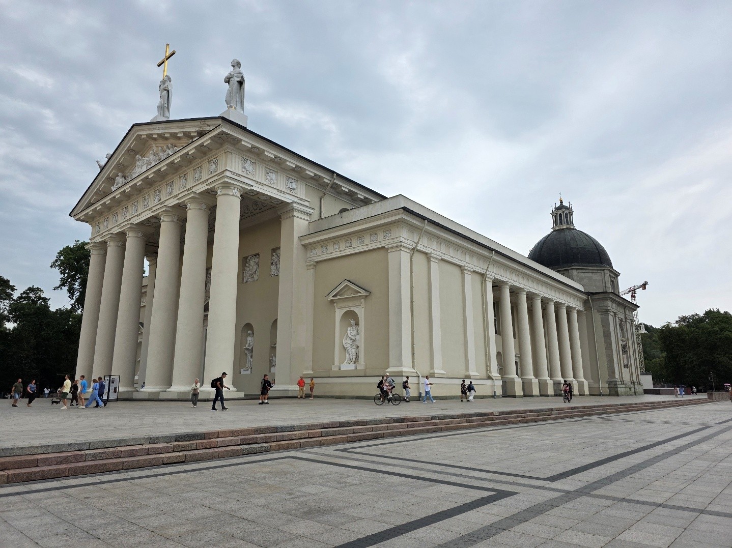 Die Kathedrale von Vilnius mit klassizistischer Fassade, Säulen und Menschen auf dem Platz davor.