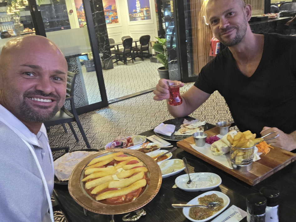 Zwei Männer sitzen an einem Tisch in einem Restaurant, essen und trinken Tee.