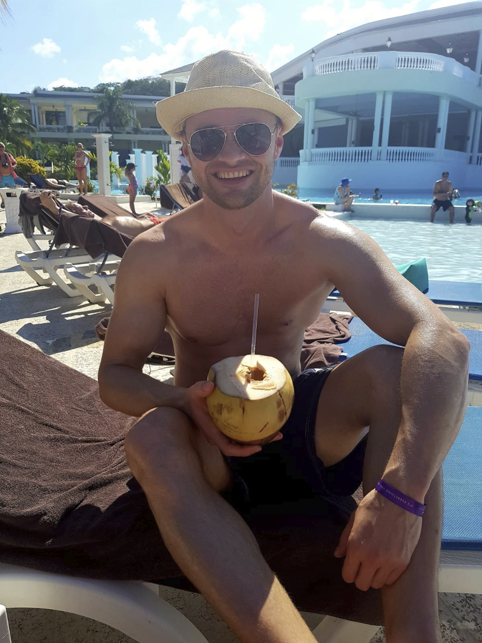 Eduard sitzt lächelnd mit einer frischen Kokosnuss an einem Pool.