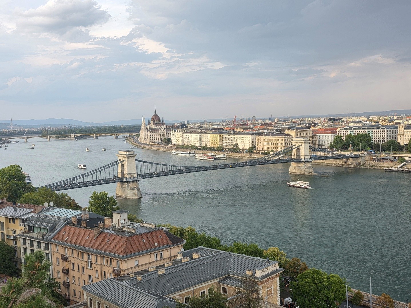 Blick von oben auf die Kettenbrücke über der Donau in Budapest mit dem Parlamentsgebäude im Hintergrund.