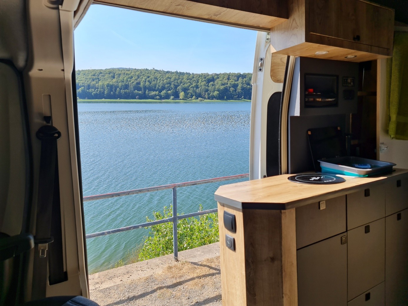 Blick aus dem Camper über die Holzküchenzeile hinaus auf einen See.