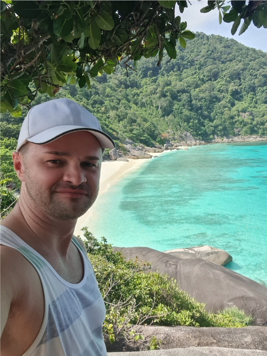 Eduard macht ein Selfie vor einem tropischen Strand mit türkisfarbenem Wasser.