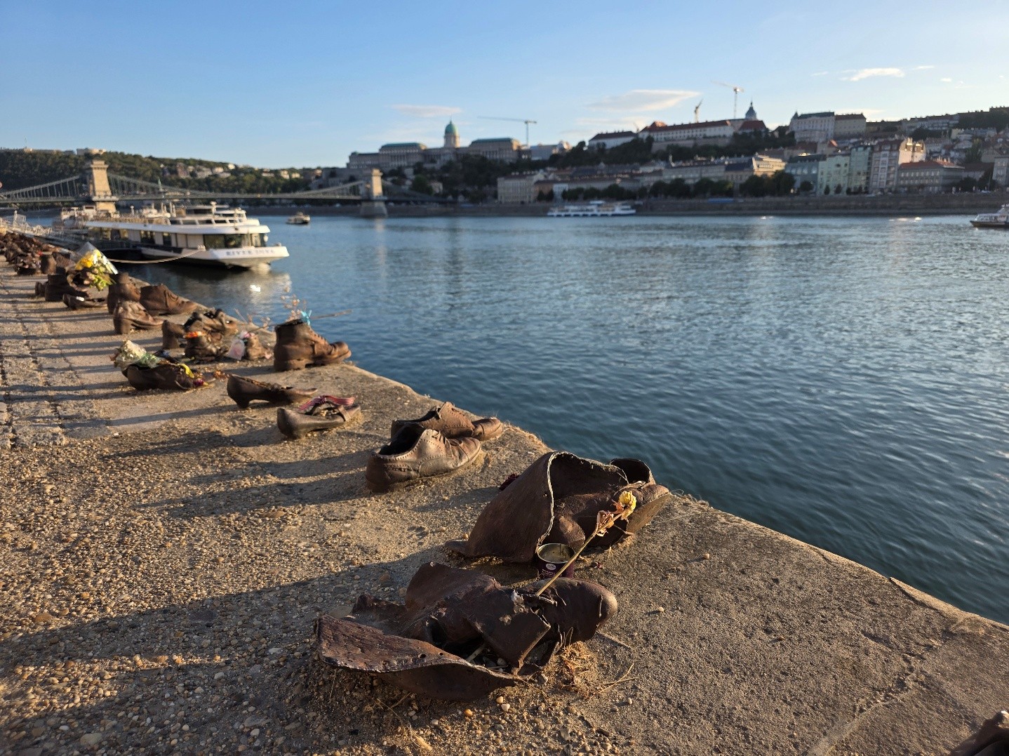 Das Mahnmal „Schuhe am Donauufer“ in Budapest mit Blick auf die Donau und die Stadt.